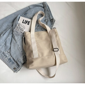 Detailed view of beige canvas tote bag with adjustable strap and reinforced stitching