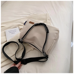Détail du sac en toile blanc cassé montrant l'anse en corde tressée et logo en cuir