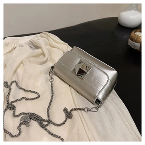 Detail of silver square crossbody bag featuring pyramid lock and brushed texture