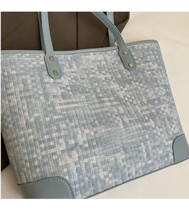 Gros plan sur un cabas tissé bleu clair avec motif pixelisé et coins en cuir souple
