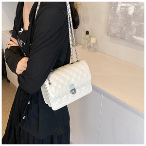Close-up of white quilted chain bag with silver hardware and leather interwoven strap
