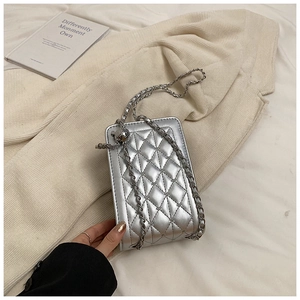 Close-up of silver quilted crossbody phone bag with metal chain strap and decorative ball