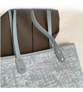 Détail du sac cabas tissé bleu clair avec poignée en cuir et rivets argentés élégants