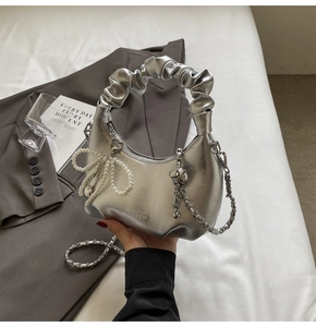 Détail du sac hobo argenté avec poignée plissée et breloque noeud en perles