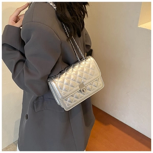 Detail of silver quilted crossbody bag with metal chain strap and turn-lock closure