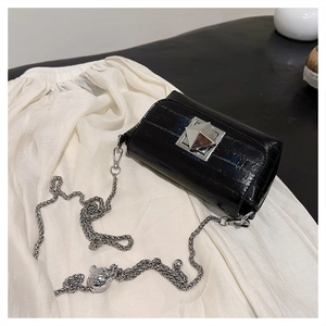 Detail of glossy black crocodile embossed leather with silver pyramid lock and chain