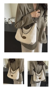 Detail view of large cream hobo bag with brown leather strap and metal chain accessory