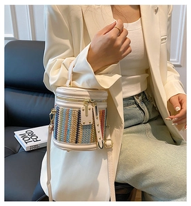 Détail du sac seau tissé coloré avec poignées en cuir blanc et fermeture éclair en métal