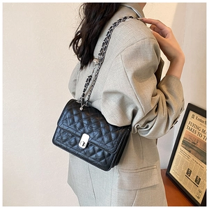 Detail view of black quilted crossbody bag with silver clasp and chain strap