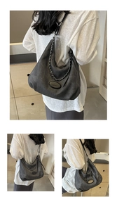 Close-up of dark grey tote bag with silver chain detail and oval metal logo accent