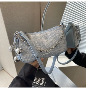 Détail du sac sous le bras tressé bleu clair avec chaîne argentée et nœud sur miroir