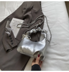 Détail du sac nuage plissé argenté avec chaîne en métal et lanière de perles décorative