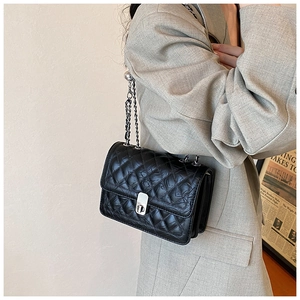 Detail of classic black quilted shoulder bag with silver chain strap and metal lock