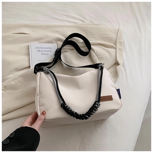 Détail du sac en toile crème avec écusson en cuir KEFEIR et poignée tressée