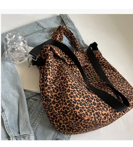 Dettaglio della borsa tote in tela leopardata con tracolla nera su giacca di jeans