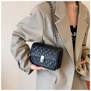 Detail view of black quilted crossbody bag with silver twist lock and chain strap