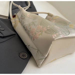 Detailed close-up of a floral silk tote bag featuring elegant oriental embroidery and slim strap