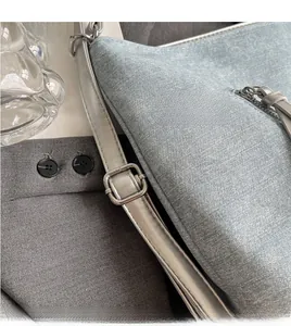 Detail of adjustable silver strap buckle and light blue denim texture tote bag