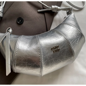Détail d'un sac croissant argenté métallisé avec logo et bandoulière nouée