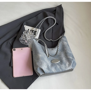 Light blue denim shoulder bag with silver chain accessory on a dark blazer