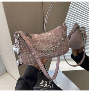 Détails d'un sac d'épaule en tweed rose avec texture tissée et breloque nœud argentée