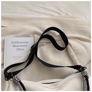Détail d'un sac cabas en toile blanche avec bandoulière noire réglable et corde tressée