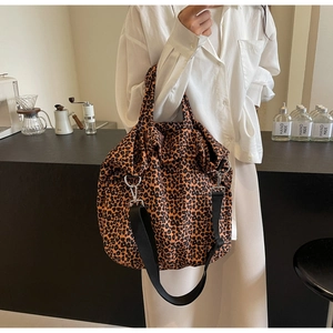 Dettaglio della borsa tote in tela leopardata con tracolla larga nera e ganci metallici