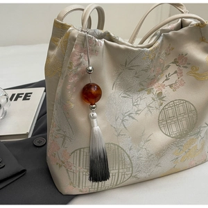 Detail of floral jacquard embroidery tote with elegant bamboo pattern and tassel charm