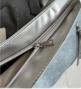 Detail view of smooth silver metal zipper and textured fabric on the large tote bag