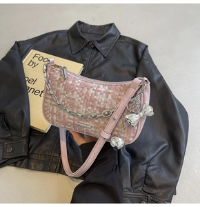 Détail du sac porté épaule tissé rose avec bandoulière en cuir et breloque nœud argent