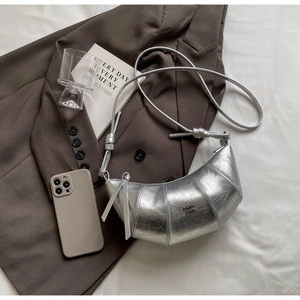 Détail du sac croissant argenté avec texte chic 2nd sur fond de blazer marron foncé