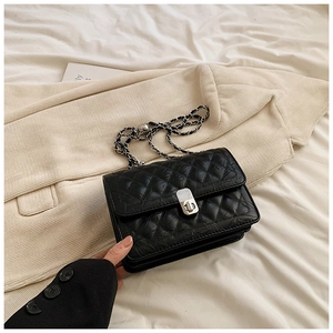 Detail of black quilted leather shoulder bag featuring silver twist-lock and chain strap