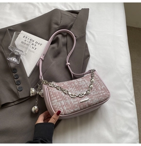 Détail d'un sac à bandoulière tissé rose avec chaîne argentée et pendentif nœud