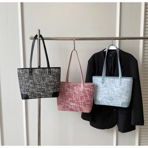 Détail des coins en cuir renforcé et logo en métal sur un sac cabas à motif pixel