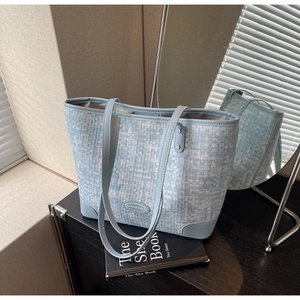 Gros plan sur un cabas tissé bleu clair avec finitions en cuir et logo de marque