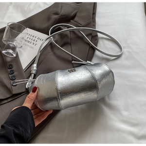 Détail du sac croissant argenté montrant le cuir texturé et le logo métallique