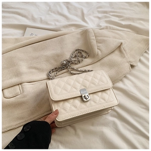 Close-up of cream quilted crossbody bag with silver chain strap and metal turn-lock closure