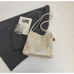 Detail of floral embroidery and beaded tassel on satin tote bag with traditional Chinese motifs
