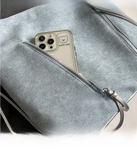 Detail shot of the spacious side zipper pocket on a blue denim texture tote bag