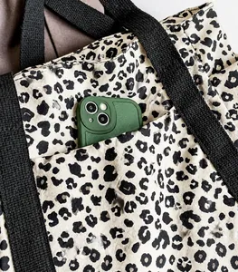 Detalle del bolso tote de lona con estampado de leopardo y bolsillo frontal para el móvil