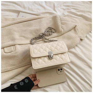 Detailed close-up of cream quilted crossbody bag with silver chain and metal clasp