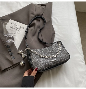 Détail du sac sous l'aisselle gris tissé avec chaîne argentée et nœud sur un blazer