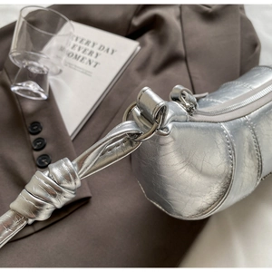 Détail du sac croissant argenté avec bandoulière à nœud et texture plissée métallique