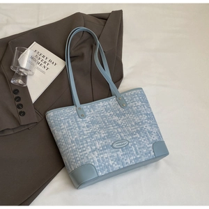 Détail du sac cabas tissé bleu et blanc avec anses en cuir sur fond de style bureau