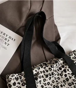 Detalle del bolso tote de lona con estampado de leopardo y correas tejidas negras duraderas