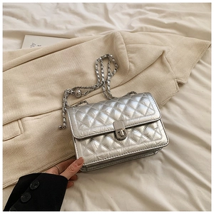 Close-up of silver quilted crossbody bag with metal chain strap and turn-lock