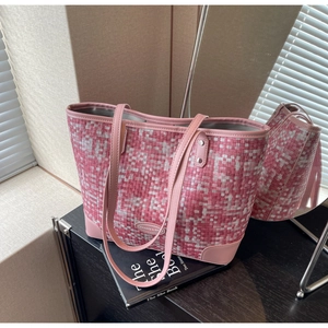 Détail du sac cabas rose tissé avec lanières en cuir et logo sur bureau en bois