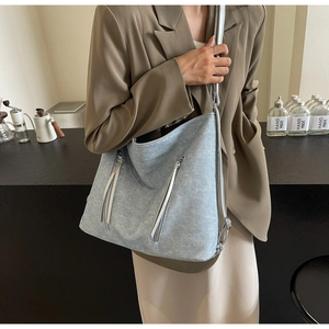 Detail of light blue denim texture hobo bag with zipper pockets for casual commuting