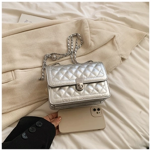 Silver quilted chain bag shown next to a smartphone to demonstrate its mini size