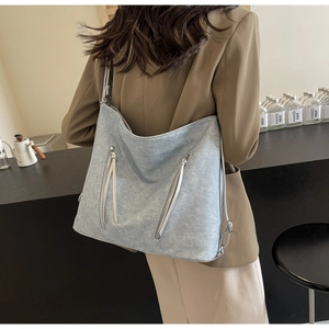 Detail view of large light blue tote with water-wash texture and silver zippers